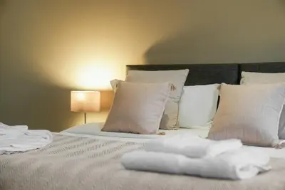 a bedroom with a bed with white pillows at The Snug - Beachwalk Apartments in Ayr