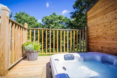 a hot tub on a deck with a wooden fence at Riverside Hideaway for Two Hot Tub River Lochay in Killin