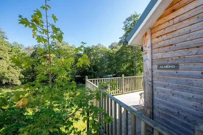a house with a wooden fence next to a porch at Riverside Hideaway for Two Hot Tub River Lochay in Killin