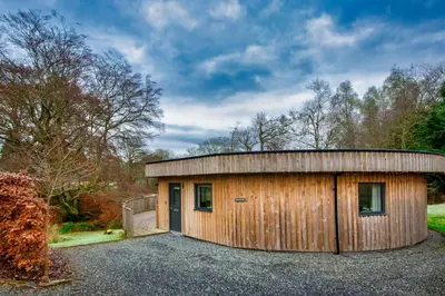 a small wooden building with a round roof at The Crannog Circular Riverside Retreat with Hot Tub in Killin