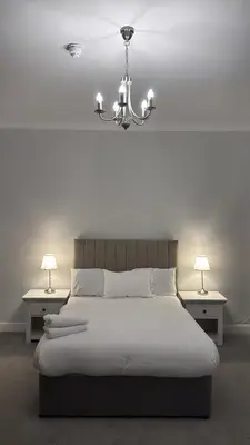 a bedroom with a bed with a chandelier and two tables at Edinburgh West Residence in Edinburgh