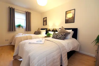 a bedroom with two beds and a window at Signature Summerhill House in Bearsden