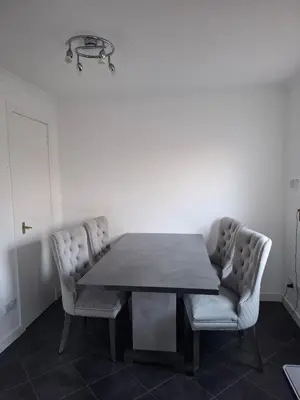 a dining room table with two chairs and a light fixture at Cheerful 3 bedroom house with free parking in Hurlet