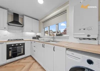 a kitchen with white cabinets and a washer and dryer at 2 Bed Home in Paisley I Sleeps 4 in Paisley