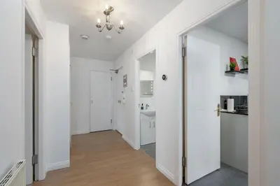 a hallway with white walls and a door to a bathroom at Stylish 2-Bed Flat with Balcony Near Haymarket - Pass the Keys in Edinburgh