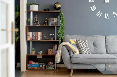 a living room with a gray couch and a book shelf at Stylish 2-Bed Flat with Balcony Near Haymarket - Pass the Keys in Edinburgh