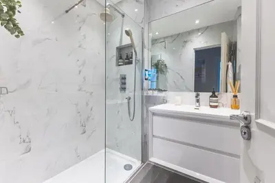 a white bathroom with a shower and a sink at Luxury MArylebone Village family home in Moffat