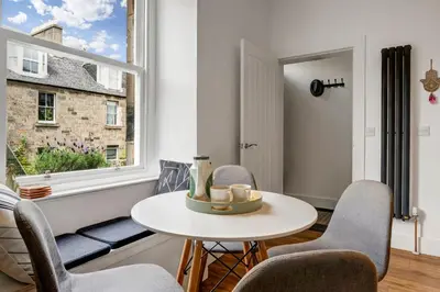 a living room with a table and chairs and a window at Stylish 2-Bed Villa Garden Central Edinburgh in Edinburgh