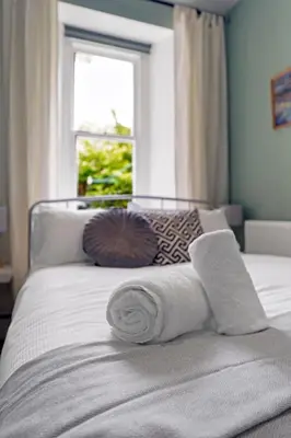 a bed with towels on it with a window at Stylish 2-Bed Villa Garden Central Edinburgh in Edinburgh