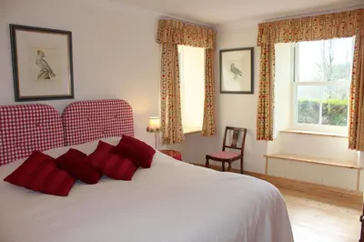 a bedroom with a white bed with red pillows at Clachandubh Cottage in Lochgilphead