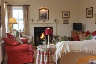 a living room with a red couch and a fireplace at Clachandubh Cottage in Lochgilphead