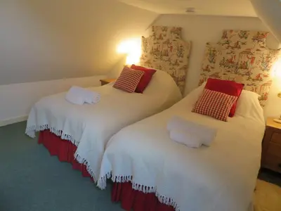 two beds in a room with white and red pillows at Finchairn Cottage in Lochgilphead