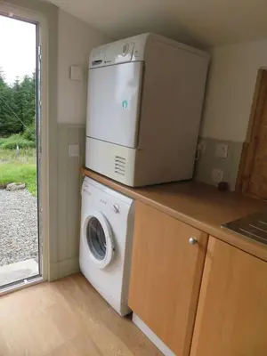 a kitchen with a washing machine and a microwave at Finchairn Cottage in Lochgilphead