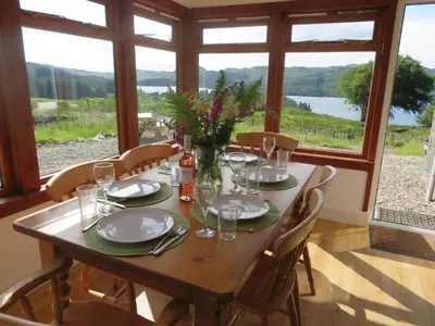 a wooden table with chairs and plates and glasses on it at Finchairn Cottage in Lochgilphead