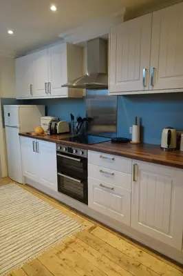 a kitchen with white cabinets and a stove top oven at School Room in Lochgilphead