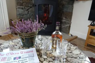 a table with a bottle of wine and some flowers at School Room in Lochgilphead
