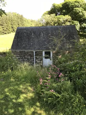 an old stone house in a field with flowers at South Lodge in Lochgilphead