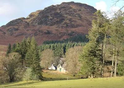 a house in a field in front of a mountain at The School House in Lochgilphead