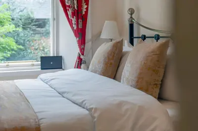 a bed with white sheets and pillows next to a window at Gardners Crescent in Edinburgh