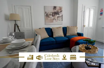 a living room with a blue couch and a table at Simpson House in Tillicoultry