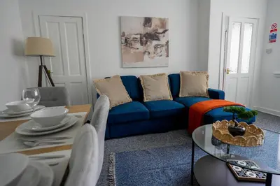 a living room with a blue couch and a table at Simpson House in Tillicoultry