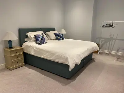 a bedroom with a large bed with pillows and a night stand at Bee Cottage in Moffat