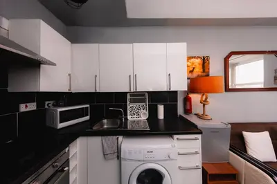 a kitchen with white cabinets and a washing machine at Calm, Cosy & Central Apartment near Meadows 10 in Edinburgh