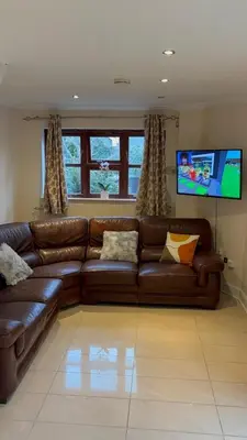 a living room with a brown leather couch and a flat screen tv at Peace Haven Hendon London NW4 in Moffat
