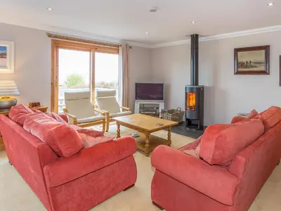 a living room with two red chairs and a fireplace at Tanglewood in Whiting Bay
