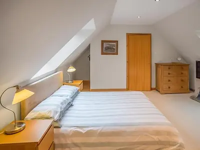 a bedroom with a large bed and a wooden dresser at Tanglewood in Whiting Bay