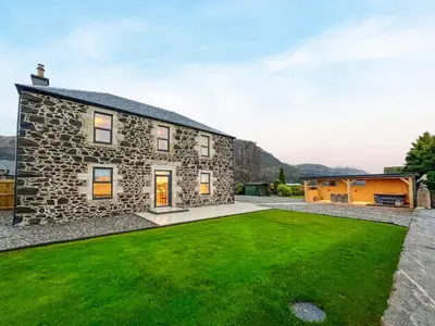 a stone house with a green lawn in front of it at Blairmains Farmhouse in Stirling
