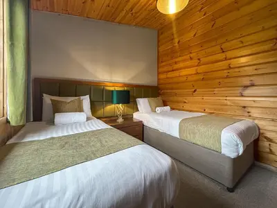two beds in a room with wooden walls at Lodge 5 - Uk51251 in Glasgow