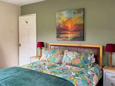 a bedroom with a bed and a painting on the wall at The Green in Lochranza