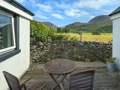 a patio with a table and chairs and a stone wall at The Green in Lochranza