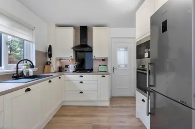 a kitchen with white cabinets and a stainless steel refrigerator at Stylish 3-Bed Home with Private Garden in Airdrie in Airdrie