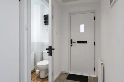 a white bathroom with a toilet and a door at Stylish 3-Bed Home with Private Garden in Airdrie in Airdrie