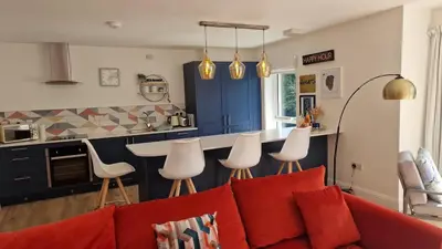 a living room with a red couch and a kitchen at Modern apartment on the river in Callander in Callander