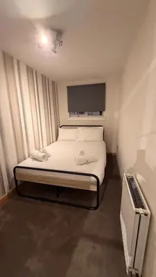 a small bedroom with a bed and a tv at Spacious Glasgow Group Stay in Glasgow