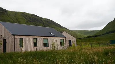 a barn in a field with mountains in the background at Auch - Cottages in Bridge of Orchy