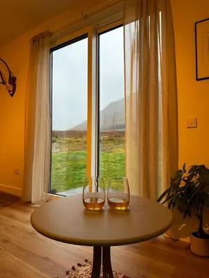 two wine glasses sitting on a table in front of a window at Auch - Trail Cabins in Bridge of Orchy