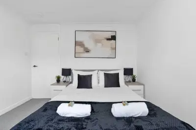 a white bedroom with a large bed with two pillows at Contractor & Family Friendly House - Sleeps 8 - FREE Parking and Fast Wi-Fi in Uphall