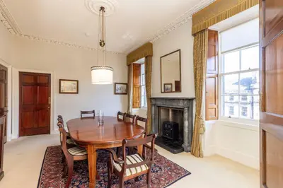 a dining room with a table and chairs and a fireplace at Top floor, central, spacious, period apartment with park views in Edinburgh