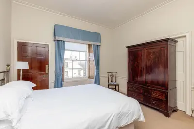 a bedroom with a bed and a dresser and a window at Top floor, central, spacious, period apartment with park views in Edinburgh