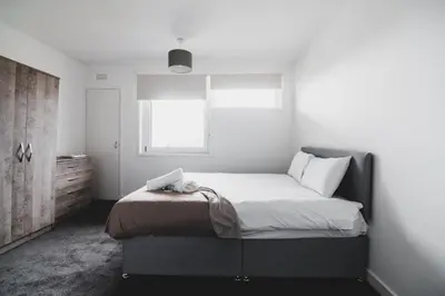 a bedroom with a large bed with a window at Glenraith property in Hogganfield