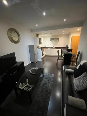 a living room with a table and a clock on the wall at City centre stylish apartment in Glasgow
