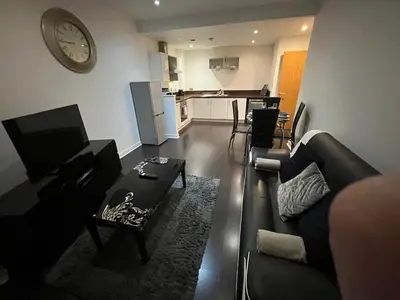 a living room with a couch and a table and a clock at City centre stylish apartment in Glasgow