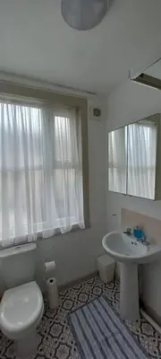 a bathroom with a toilet and a sink and a mirror at Town centre 3 bedroom flat in Moffat
