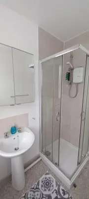 a white bathroom with a shower and a sink at Town centre 3 bedroom flat in Moffat