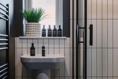 a bathroom with a sink and bottles on a shelf at JW Canmore ApartHouse in Glasgow