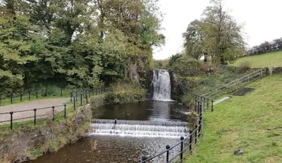 a waterfall in the middle of a park with a pond at Newton Mearns Home in Newton Mearns